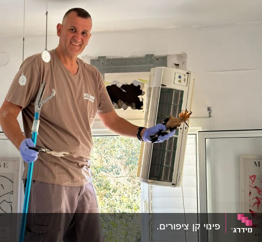 אדם עם כפפות מחזיק כלי עבודה ליד מזגן
